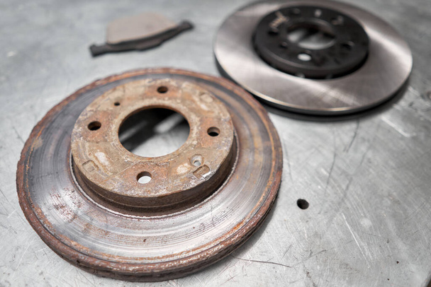 Old used and new to change for safety car brake disc and pad on metal table of an auto mechanic. Auto repair concept. - Photo, Image