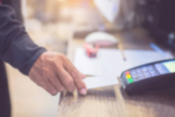 Blurry business payment background. Hand put credit card In slot of credit card reader, credit card payment, buy and sell products & service, the concept of payment without cash. - Φωτογραφία, εικόνα