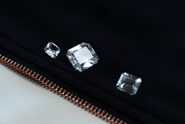 white diamond or gemstone in emerald cut on black fabric with gold zipper  fashion background - Photo, Image