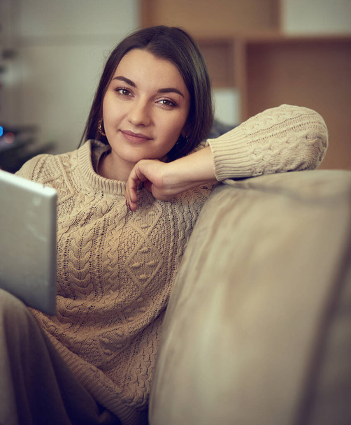 Woman using electronic tab sitting in couch - 写真・画像