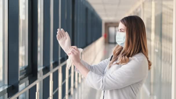 A nurse in a respirator is putting disposable rubber white gloves - Felvétel, videó