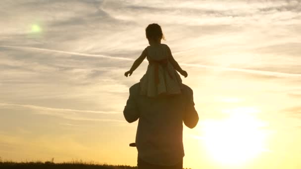 Отец с любимой дочерью на плечах танцует в полете и смеется. Счастливый ребенок играет со своим отцом на закатном поле. Силуэт мужчины и ребенка. Концепция семьи и детства
 - Кадры, видео