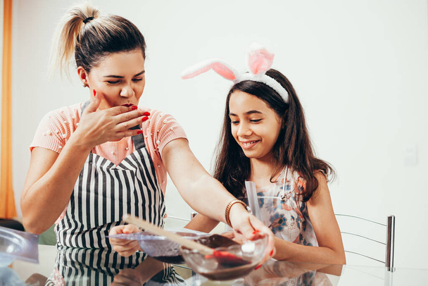 Mother and daughter making homemade chocolate easter eggs. Easter in Brazil. - Photo, Image