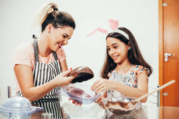 Mother and daughter making homemade chocolate easter eggs. Easter in Brazil. - Foto, Bild