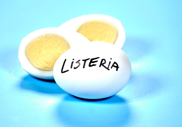 Huevo duro con Listeria escribiendo sobre el huevo sobre fondo azul. La listeriosis es una infección transmitida por alimentos causada por la bacteria Listeria. La listeria es causada por bacterias que pueden crecer a temperaturas frías
 - Foto, imagen
