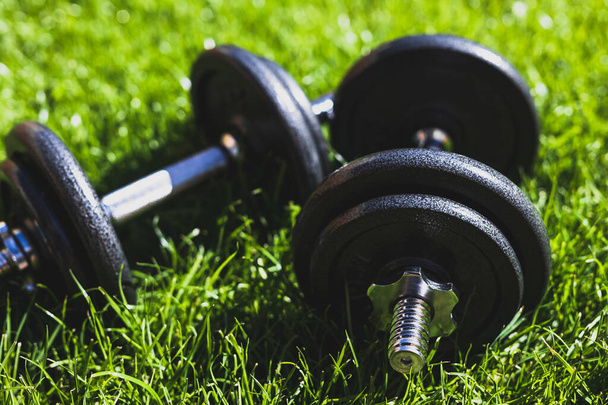 keeping fit and exercising outdoor or at home, set of heavy dumbbells on green grass lawn in a backyard under direct sunlight - Фото, зображення