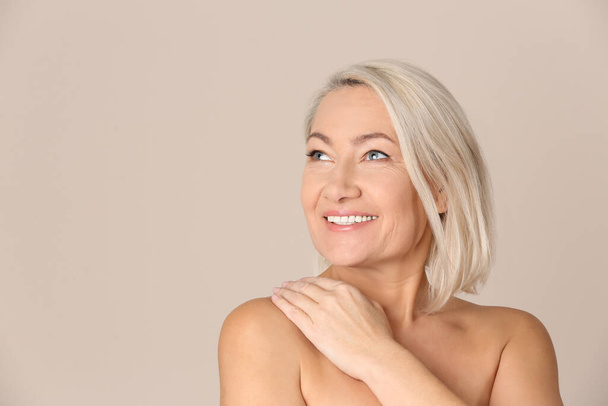 Portrait of beautiful mature woman on beige background. Space for text - Fotografie, Obrázek