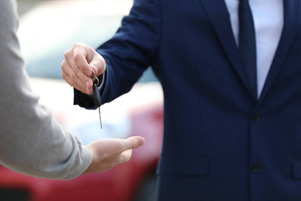Sprzedawca daje klucz do klienta w nowoczesnym salonie samochodowym, zbliżenie. Kupowanie nowego samochodu - Zdjęcie, obraz