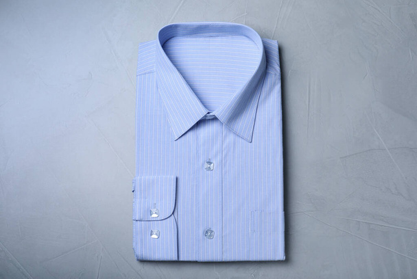 Stylish light blue shirt on grey background, top view. Dry-cleaning service - Foto, Bild