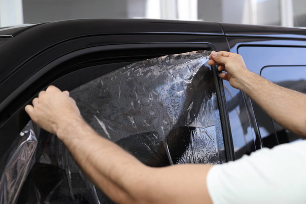 Worker tinting car window with foil in workshop, closeup - 写真・画像