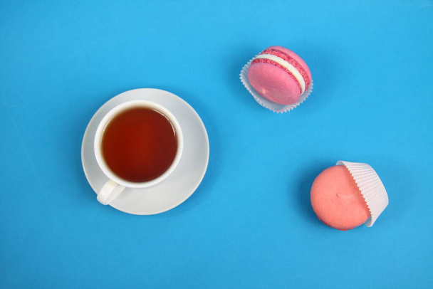 cup of tea and two macaroons on blue background flat lay. Image contains copy space - Foto, Imagem