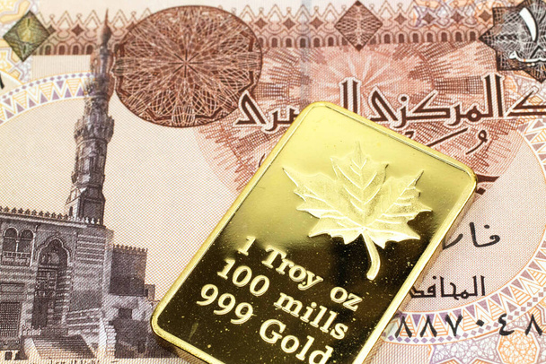 A macro image of a one pound Egyptian pound note with a gold bar.  Shot close up. - Photo, Image