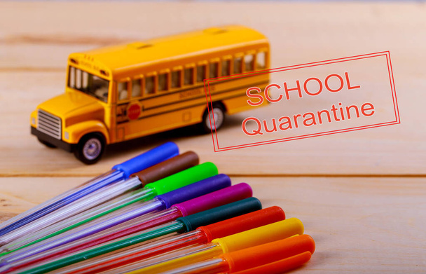 SCHOOL Quarantine global pandemic corona virus covid-19 Back to school supplies colored pencils and toy yellow school bus on wooden background - Zdjęcie, obraz