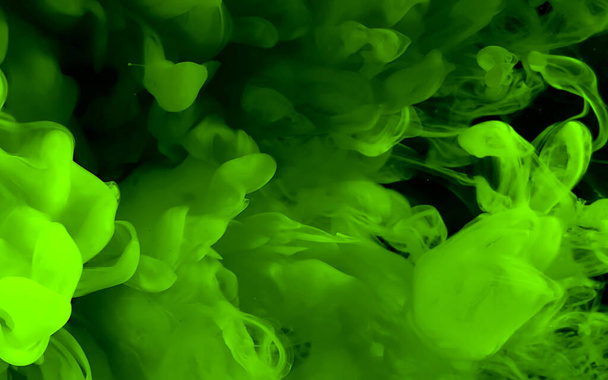 Zielony tusz akwarelowy w wodzie na czarnym tle. Kosmiczne magiczne tło. Zielone abstrakcyjne tło. Fajny wygaszacz ekranu trendów. - Zdjęcie, obraz