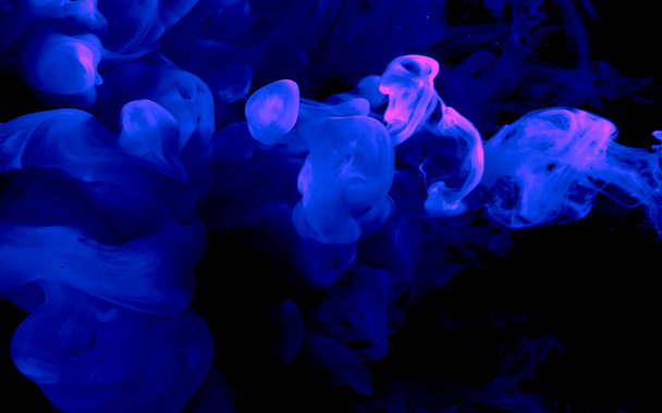 Blue watercolor ink in water on a black background. Cosmic magic background. Blue abstract background. Cool trending screensaver. - Фото, зображення