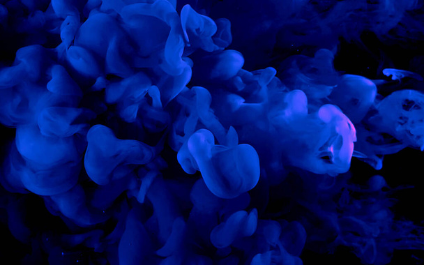 Blue watercolor ink in water on a black background. Cosmic magic background. Blue abstract background. Cool trending screensaver. - Foto, afbeelding