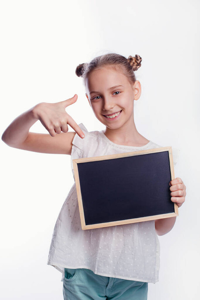 Beyaz arka planda boş bir tahta tutan küçük bir kız. Çocuk boş bir tahta gösteriyor. Eğitim kavramı - Fotoğraf, Görsel