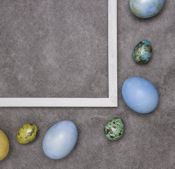 Huevos de Pascua de colores cerca de una parte de un marco blanco de madera sobre un fondo gris. Feliz Pascua
! - Foto, imagen