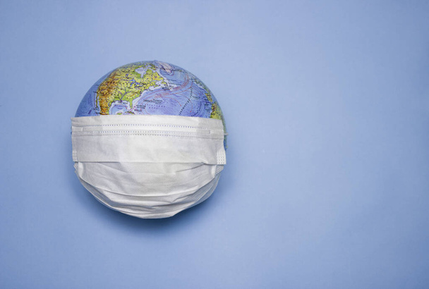 Disposable medical mask on the globe, model of the Earth. The concept of a pandemic. COVID-19, coronavirus. World epidemic of the disease. COVID Dangerous virus. - Valokuva, kuva