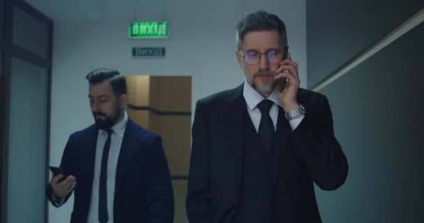 Businessman phoning in office corridor - Πλάνα, βίντεο