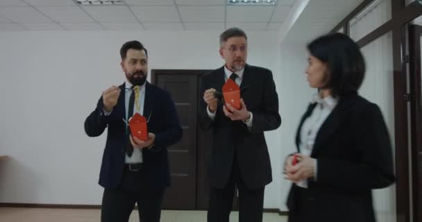 Empresarios charlando y comiendo en pasillo de oficina
 - Metraje, vídeo