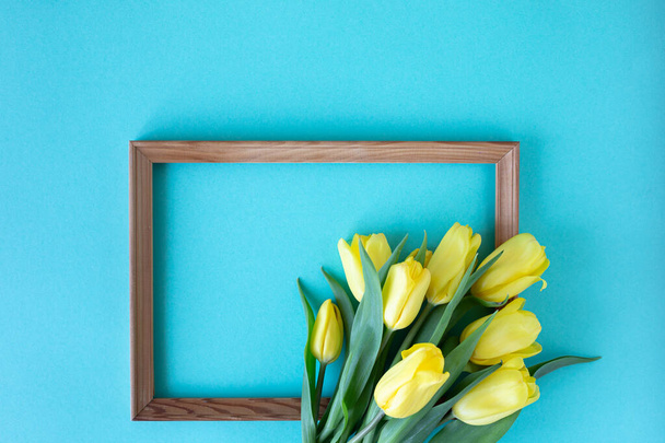 Beautiful flower arrangement. Yellow flowers tulips, empty frame for text on a blue background. Wedding. Birthday Valentine's Day. Mothers Day. Flat lay, top view - 写真・画像