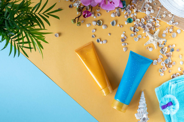 Zonnecrème flessen, glazen, zeesterren, palmbladeren op een gele achtergrond. Schoonheid en zorg in de zomer. Vakantie op zee. bovenaanzicht - Foto, afbeelding