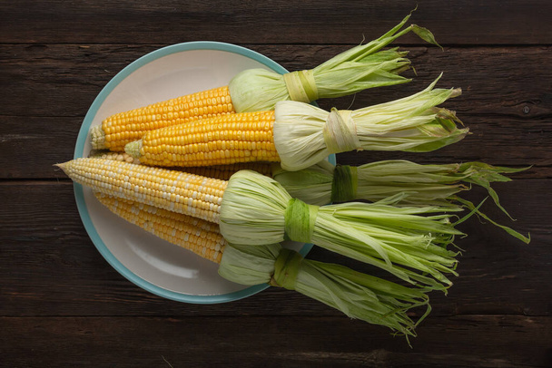 Maïs en épi sur un plat blanc, vue de dessus
 - Photo, image