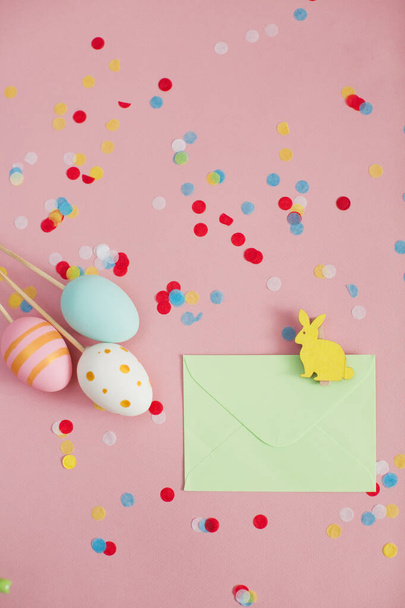 Easter eggs and envelope with easter bunny on a pink background with colorful confetti. Easter decorations - Fotoğraf, Görsel