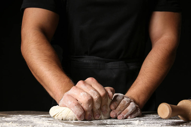 Man kneading dough in kitchen, closeup - Foto, imagen