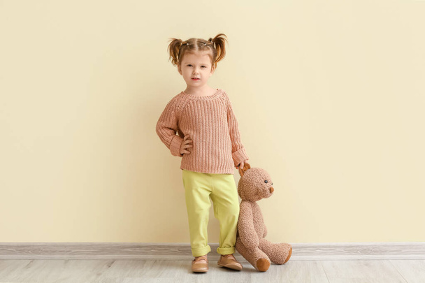 Χαριτωμένο κοριτσάκι με αρκουδάκι κοντά σε ανοιχτό τοίχο - Φωτογραφία, εικόνα