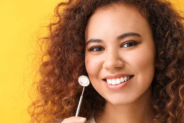 Молодая женщина с зеркалом дантиста на цветном фоне
 - Фото, изображение
