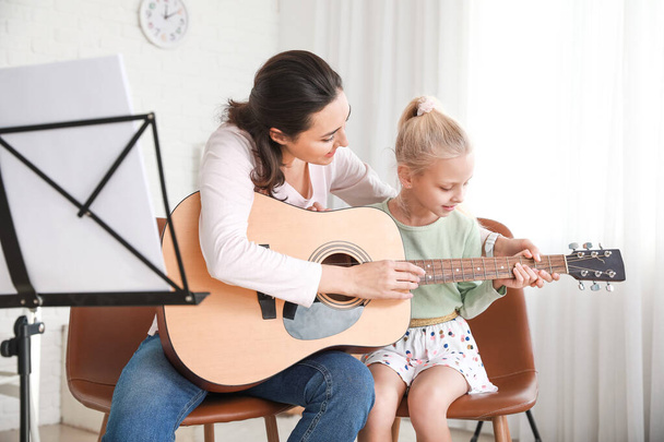 Prywatny nauczyciel muzyki daje lekcje gry na gitarze małej dziewczynce w domu - Zdjęcie, obraz