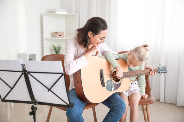 Yksityinen musiikinopettaja antaa kitara oppitunteja pieni tyttö kotona
 - Valokuva, kuva