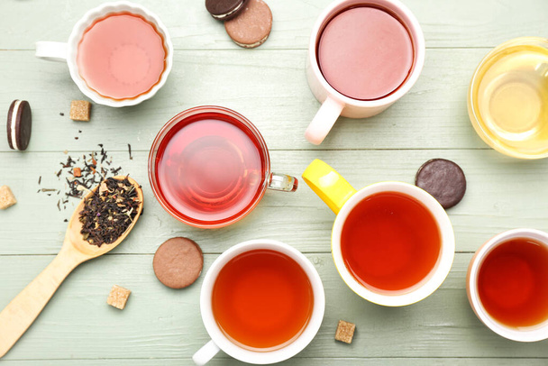 Чашки с различными видами горячего чая на деревянном фоне
 - Фото, изображение