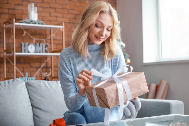 Beautiful young woman wrapping Christmas gifts at home - Photo, image