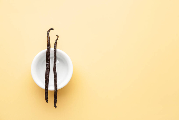 Bowl with aromatic vanilla sticks on color background - Foto, imagen