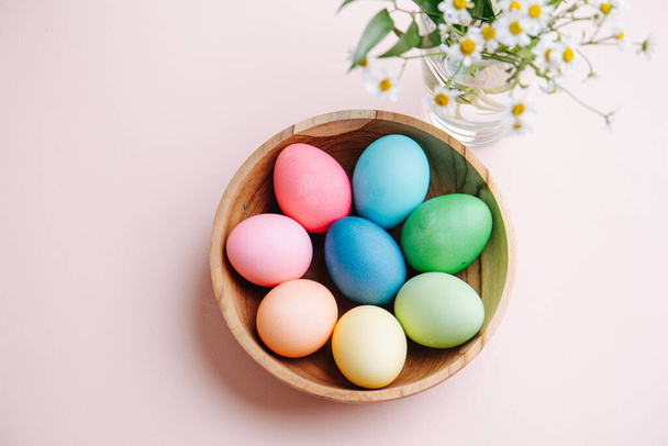 Easter holiday concept. Easter picture, multi-colored eggs in a wooden plate, on a pink background - Valokuva, kuva
