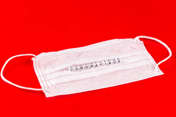 Coronavírus palavra feita de letras sobre fundo vermelho. A inscrição na máscara protetora médica coronavírus
. - Foto, Imagem