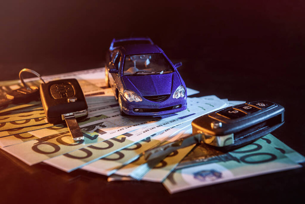 Игрушечный автомобиль с ключами на евробанкнотах черного цвета
  - Фото, изображение