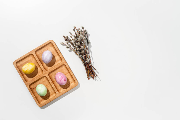 Colorful Easter eggs on wooden board and pussy-willow twigs. White background. Top view. - Fotó, kép