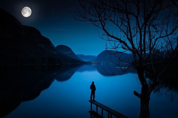 man die door lake, bedekt met maanlicht - Foto, afbeelding