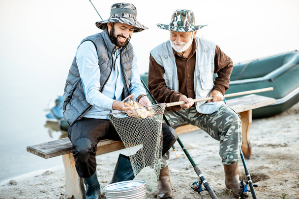 Grandfather with son fishing on the lake - 写真・画像