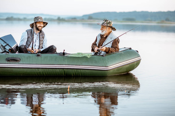 Дедушка с сыном рыбачит на лодке
 - Фото, изображение