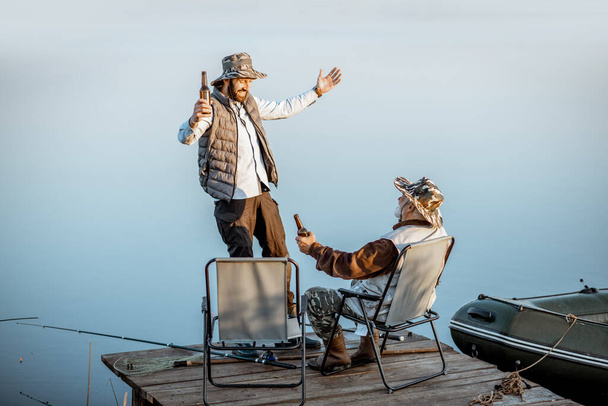 Grandfather with adult son talking on fishing - Photo, Image