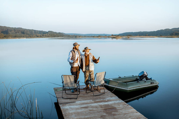 Grandfather with adult son fishing on the lake - Foto, afbeelding