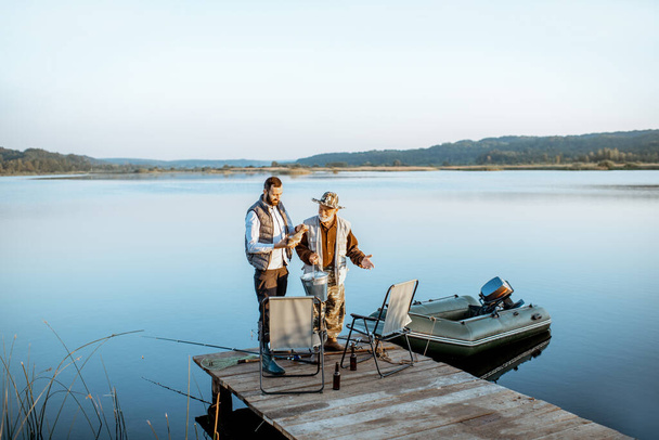 Grand-père avec fils adulte pêche sur le lac
 - Photo, image