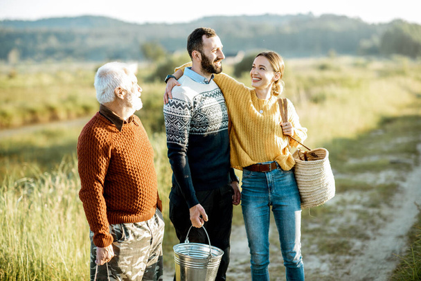 Young man and woman with senior grandfather walking outdoors - Foto, afbeelding