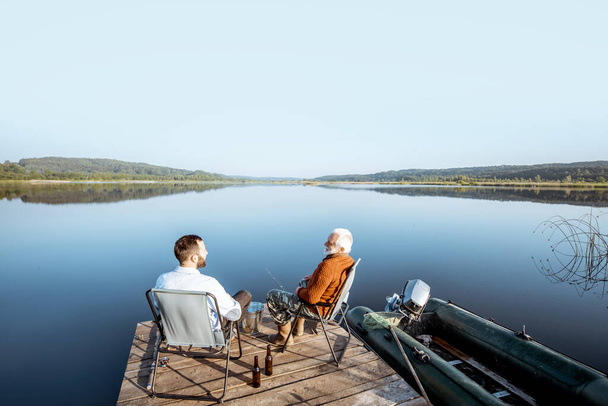 Abuelo con hijo adulto pesca en el lago
 - Foto, Imagen