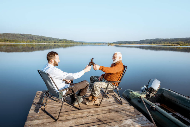 Grandfather with adult son fishing on the lake - Fotoğraf, Görsel